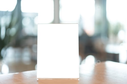 Preview: Restaurant menu frame with white blank screen on wooden table in restaurant or cafe on background