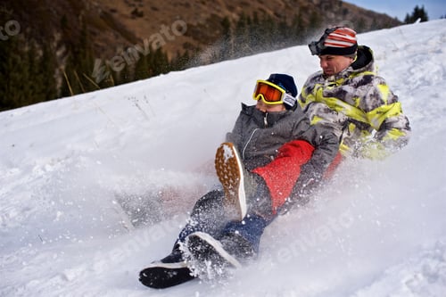 Preview: Young man and little boy have fun on sleds and descend from the snow slide