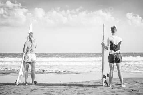 Preview: Friends surfers standing on the beach with surfboards preparing to surf on high waves