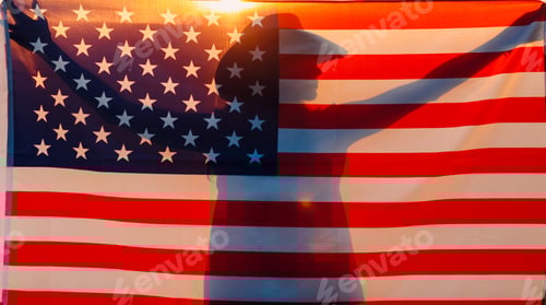 Preview: Woman silhouette in the agricultural field beyond the American Flag on sunset