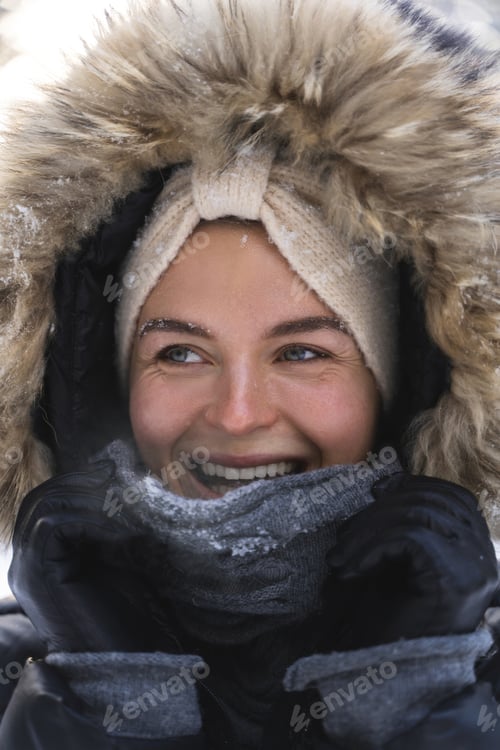Preview: Young and cheerful woman wearing jacket with a hoodie during cold winter day