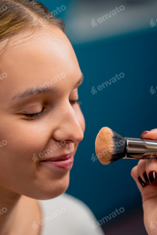 Preview: close-up make-up artist applies cosmetic foundation with a brush to client's face in a beauty salon