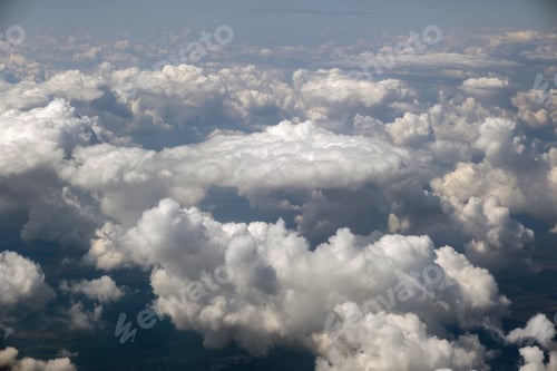 Preview: Aerial view from airplane window of white puffy clouds on bright sunny day