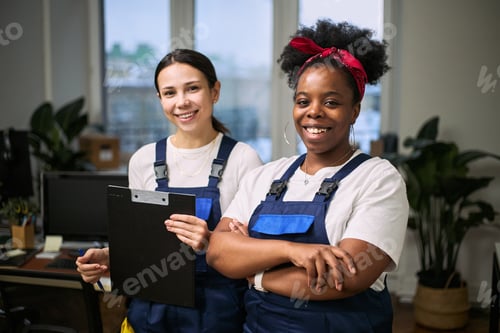 Preview: Portrait of Young Adult Caucasian Woman and Black Woman Smiling in Office