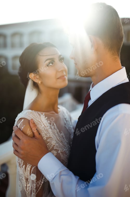 Preview: Stylish couple of happy newlyweds posing at sunset. Sexy kissing stylish couple of lovers at sunset.