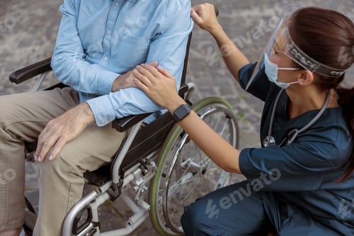 Preview: Cropped shot of nurse wearing face shield and mask holding hand, supporting mature man, recovering