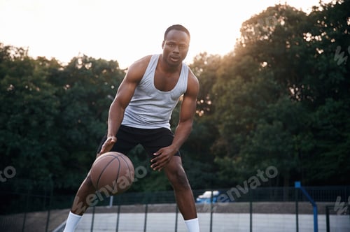 Preview: Playing the game. Young black man is with basketball ball outdoors