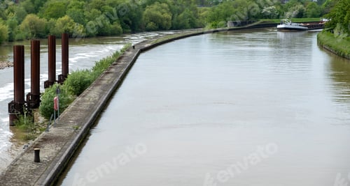 Preview: Neckar River Heidelberg city Germany. Vessel sails in calm water, pavement separates the waterway.