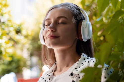 Preview: Young woman enjoying music with headphones in a garden
