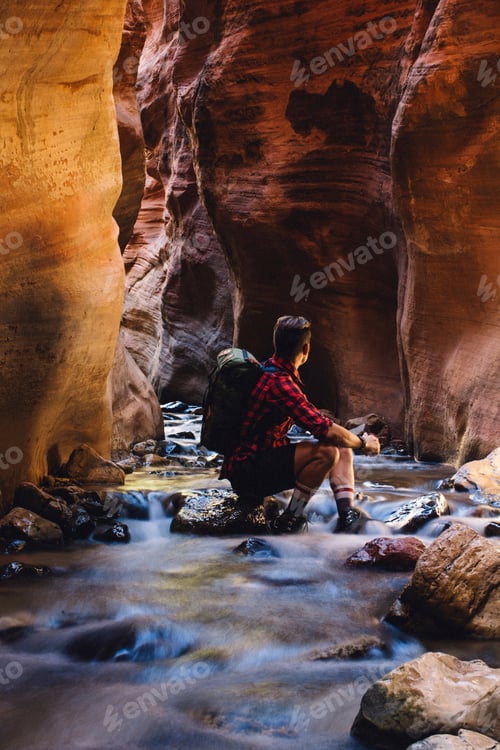 Preview: Hiker resting by a serene river in a canyon
