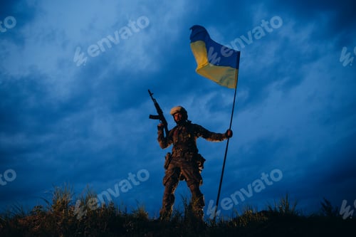 Preview: Ukrainian armed soldier is holding a national flag after the battle