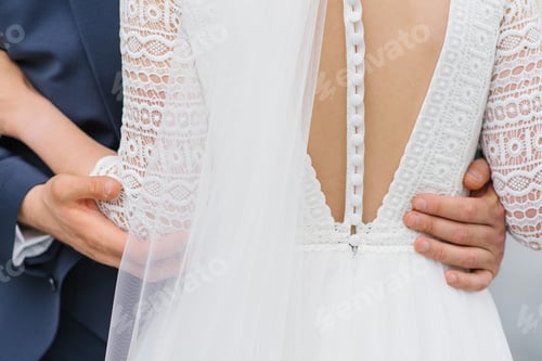 Preview: Beautiful bridesmaid dress back with numerous buttons. The groom embraces the bride's waist