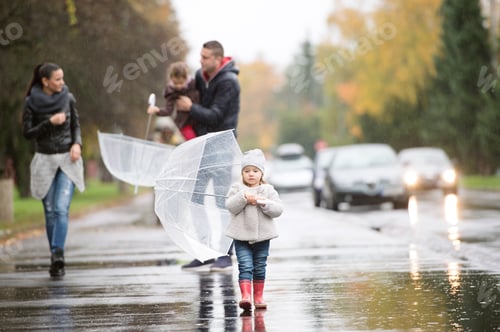 Preview: Family with daughters under the umbrellas. Walk on rainy day.