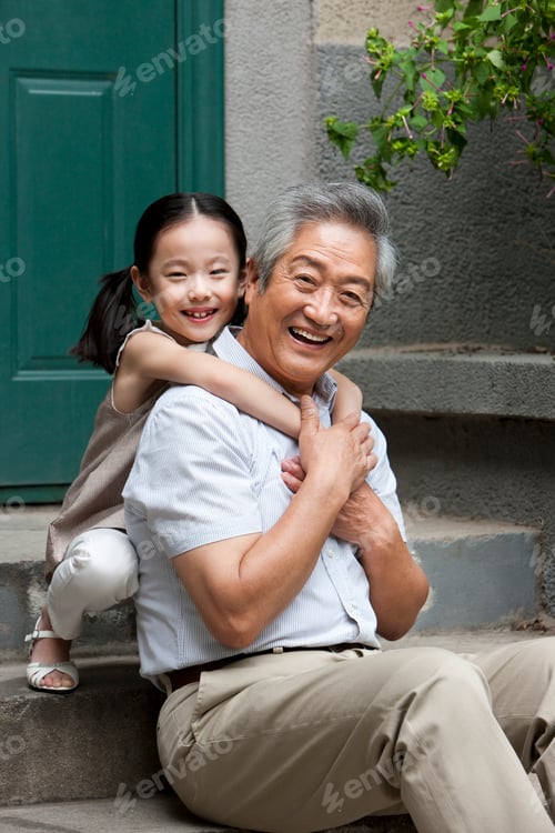 Vista previa: Chinese grandfather and grandaughter embracing on front stoop