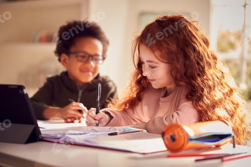 Preview: Two Children Sitting At Kitchen Counter Doing Homework Using Digital Tablet