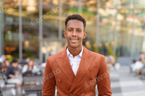 Preview: Portrait of handsome black African businessman smiling outdoors in city