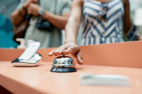 Preview: Close-up of woman pressing service bell at hotel reception.