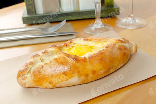Preview: Freshly baked khachapuri served on a wooden table during breakfast in a cozy cafe