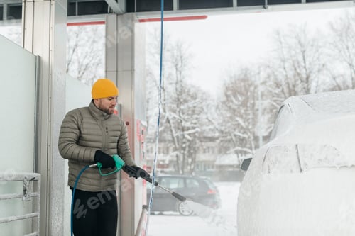 Preview: Man washing car with pressure washer in winter