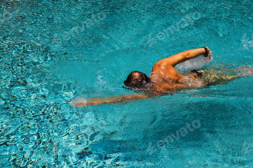 Preview: Young man is swimming in a transparent pure water of a pool in a sunny day.