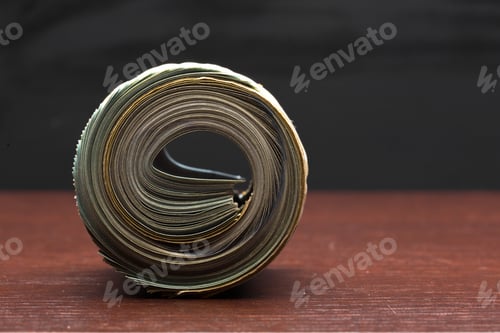 Preview: Rolled stack of old banknotes on wooden table against black background