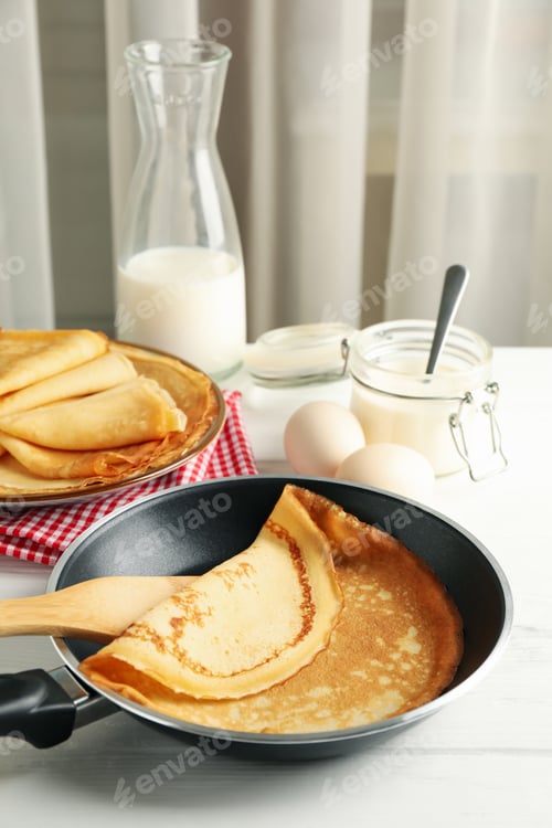 Preview: Concept of tasty breakfast with thin pancakes on white wooden table