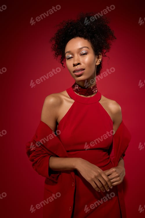 Preview: Elegant young woman in red attire with a captivating smile in a vibrant setting