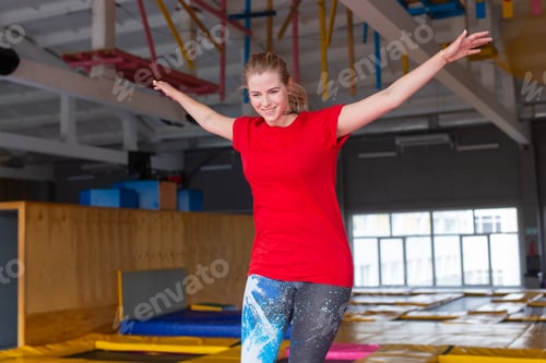 Preview: Fitness, fun, leisure and sport activity concept - Young happy woman jumping on a trampoline indoors
