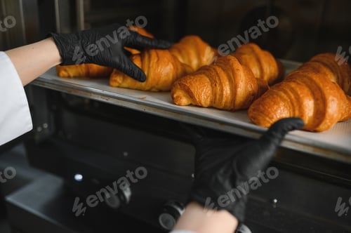 Preview: Baker taking freshly baked croissants out of oven