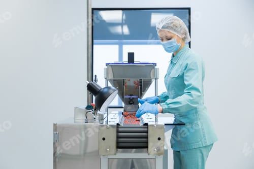 Preview: Pharmacy industry woman worker in protective clothing operating production of tablets in sterile