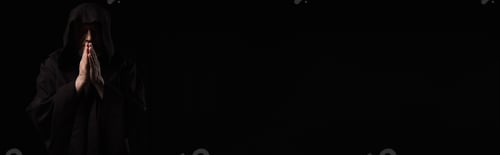 Preview: front view of medieval monk in dark hood praying isolated on black, banner