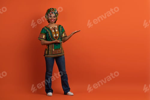 Preview: Smiling african woman in traditional costume showing empty space