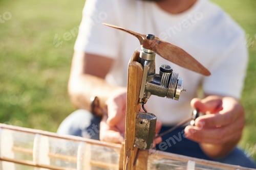 Preview: Made of wood. Man is on the field fixing the toy plane