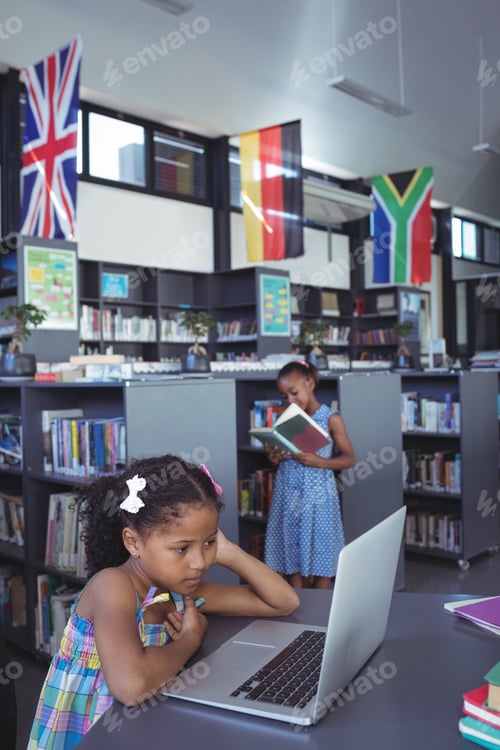 Preview: Concentrated girl looking at laptop in library