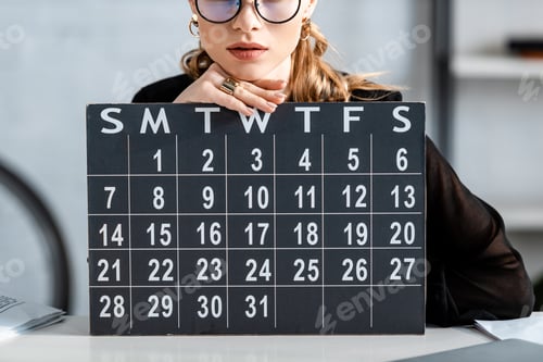 Preview: businesswoman in black clothes and glasses holding calendar