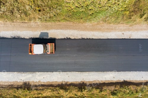 Preview: Aerial view of new road construction with steam roller machine at work.