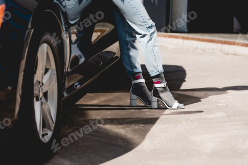 Preview: cropped view of fashionable young woman posing near car