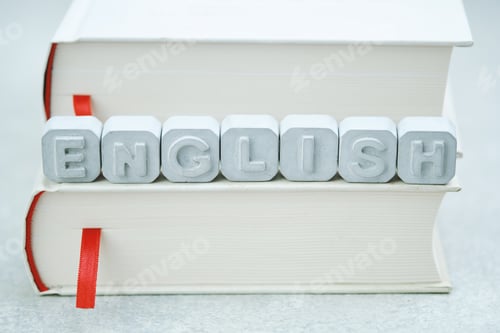 Preview: Word English made from gray concrete letters on a white book. English language studying