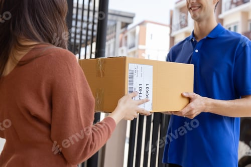 Preview: Caucasian Delivery Man in Uniform Delivering a Carton Parcel Box to a Woman