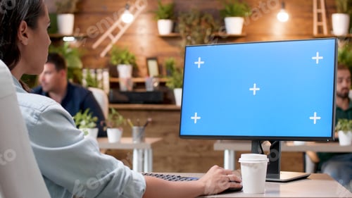 Preview: Businesswoman sitting at desk looking at mock up green screen chroma key computer