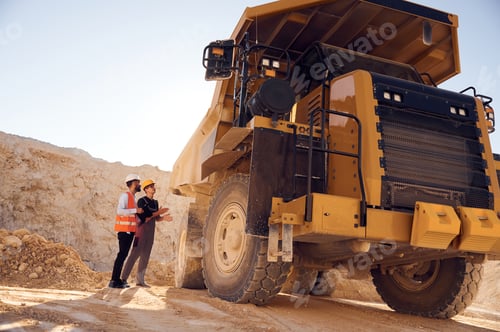 Preview: Looking at big haul truck. Two men in uniform are working together in the quarry