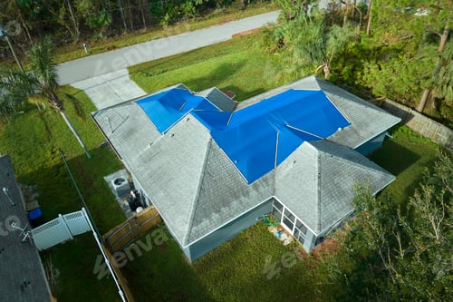 Preview: Hurricane Ian damaged house rooftop covered with protective plastic tarp against rain