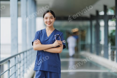Preview: Young confident doctor smiling and holding stethoscope in hospital corridor
