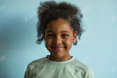 Preview: Portrait of Black Girl Smiling Against Blue Background Looking at Camera