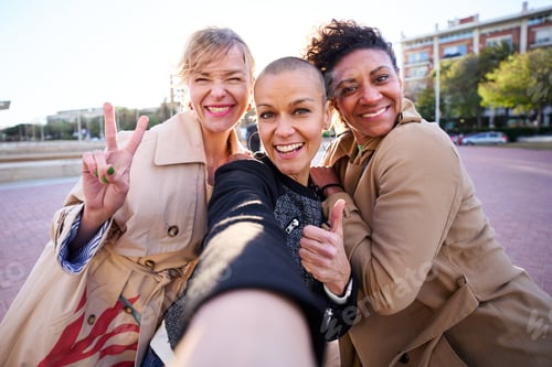 Preview: POV selfie mobile of three middle-aged multiracial women looking smiling camera outdoor. Group.