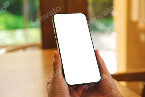 Preview: Mockup image of a woman holding and using mobile phone with blank desktop at home