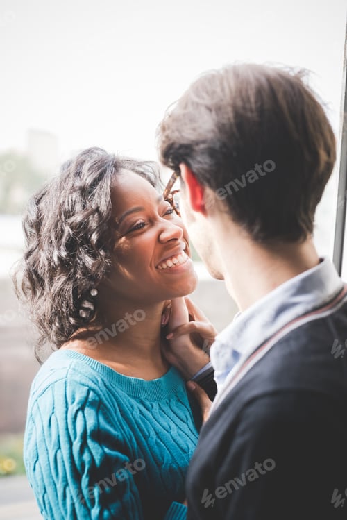 Preview: multiethnic couple of lover having fun and hugging indoor in their house