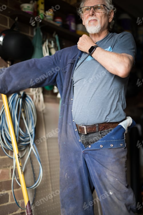 Senior Man Tries on Blue Overalls at Home