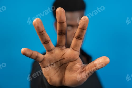 Preview: Businessman showing stop sign with hand on blue background