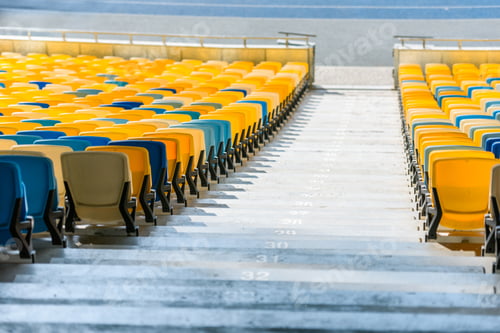 Preview: rows of yellow and blue stadium seats and stadium stairs